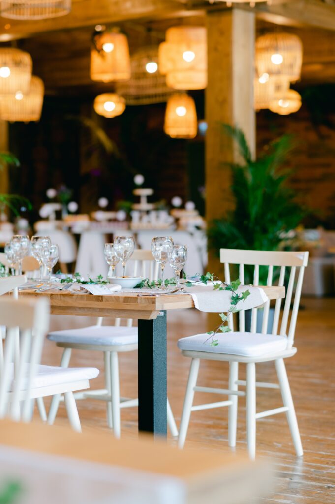 A decorated table at a wedding or large event, with glasses and white decor.