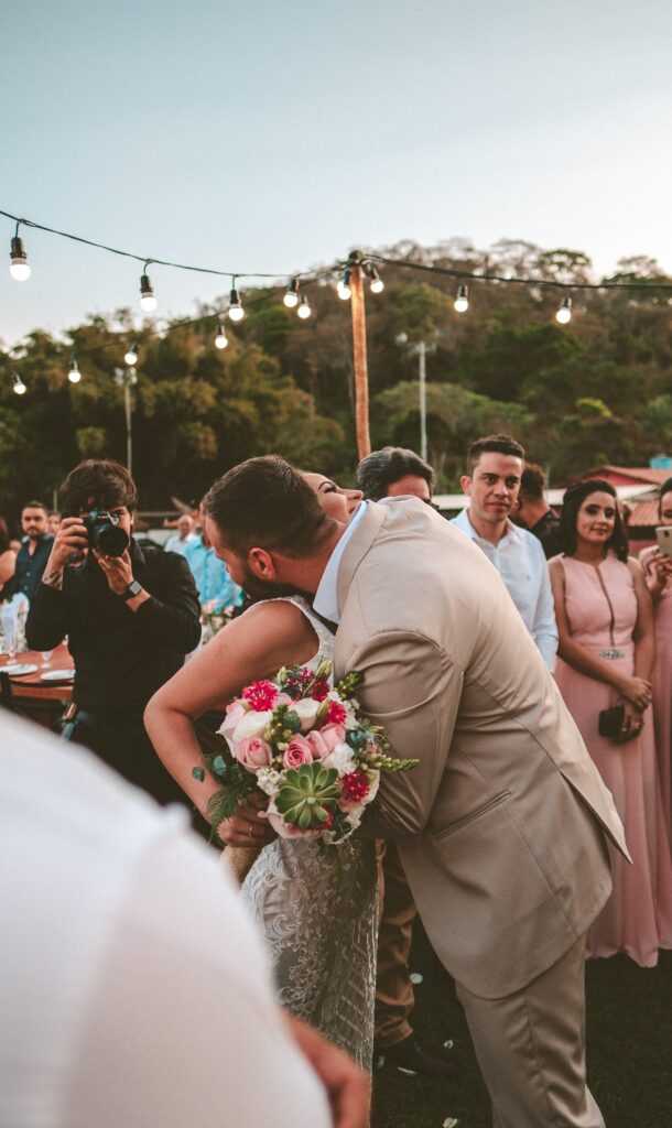 a photographer in the background at a wedding, couple embracing